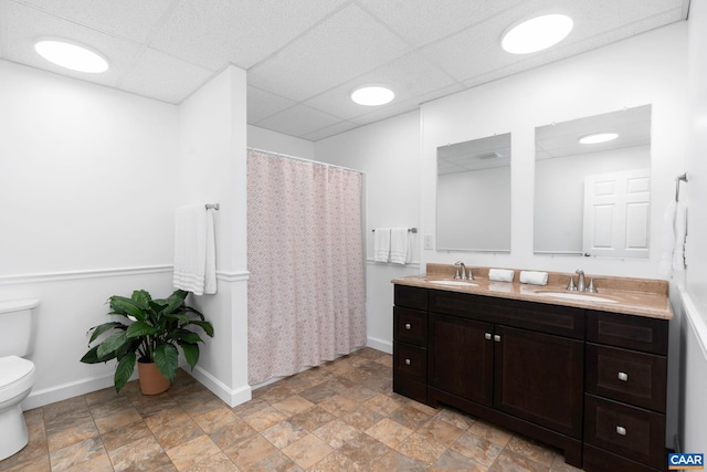 bathroom featuring double vanity, a sink, toilet, and baseboards