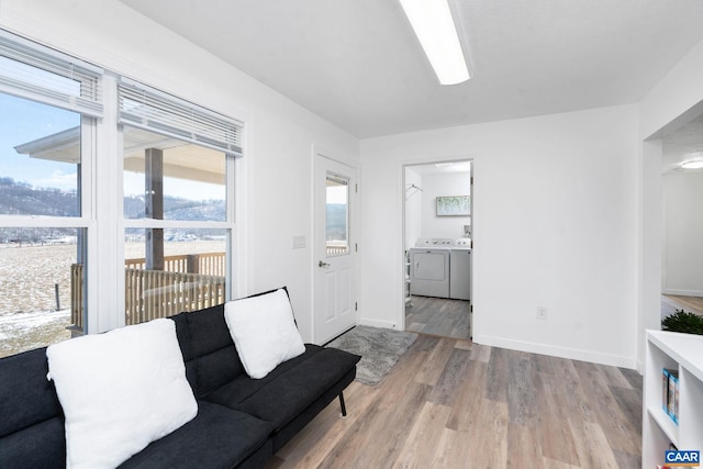 living area with wood finished floors, plenty of natural light, baseboards, and separate washer and dryer