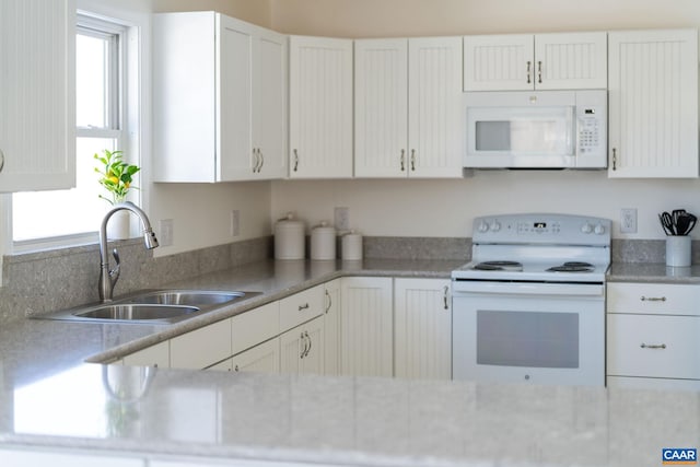 kitchen featuring white appliances, white cabinetry, and a sink