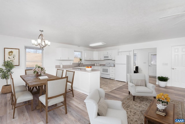 dining space with a textured ceiling, light wood finished floors, and a notable chandelier