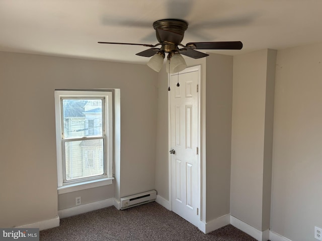 unfurnished bedroom featuring a baseboard heating unit, dark carpet, a ceiling fan, and baseboards