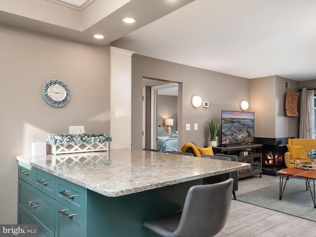 kitchen featuring light wood-style floors, light stone counters, open floor plan, and recessed lighting