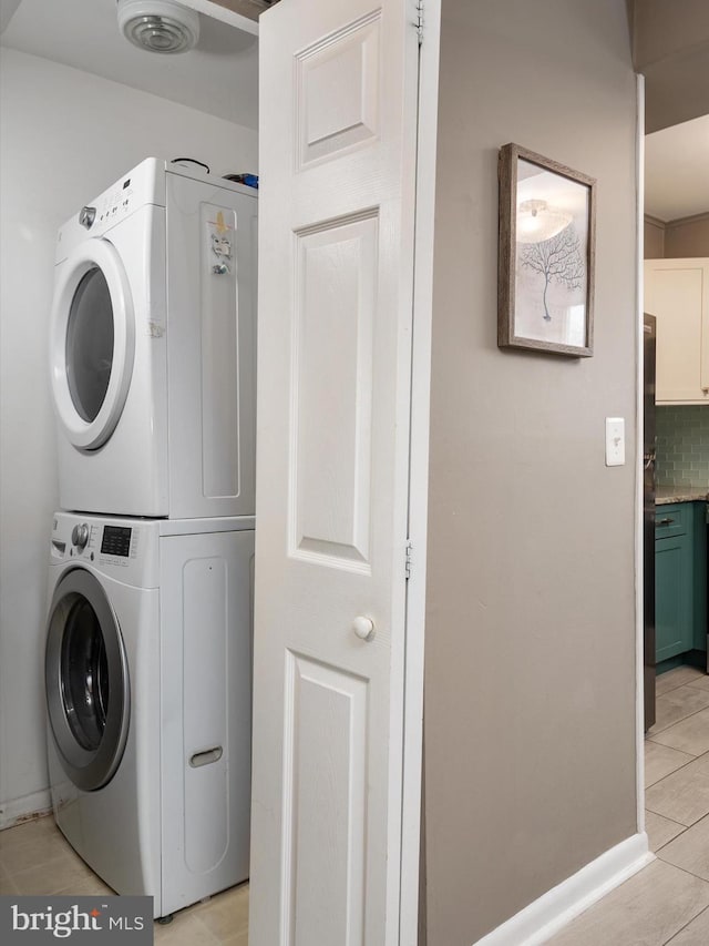 clothes washing area featuring stacked washer / dryer, laundry area, and baseboards