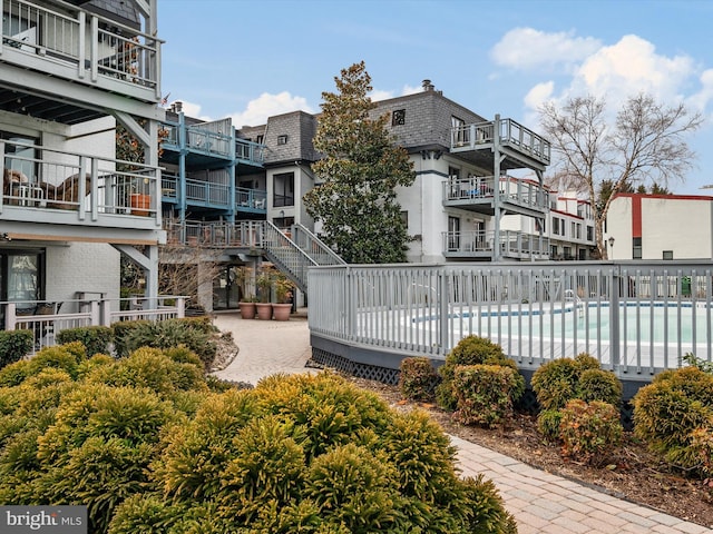 view of community featuring a water view, a pool, and a patio