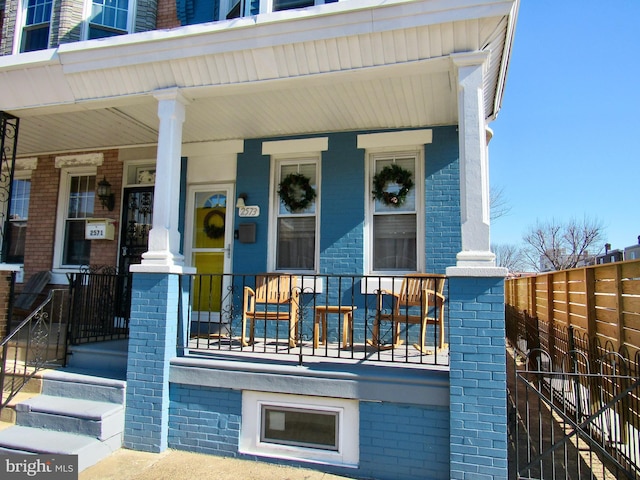 doorway to property with covered porch and brick siding