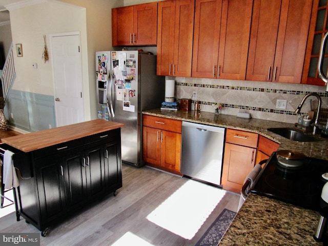 kitchen with decorative backsplash, light wood-style flooring, appliances with stainless steel finishes, light stone counters, and a sink