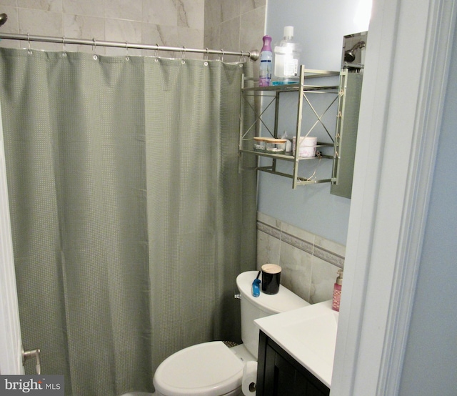 bathroom with tile walls, toilet, wainscoting, vanity, and a shower with curtain