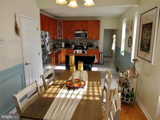 kitchen featuring tasteful backsplash, glass insert cabinets, appliances with stainless steel finishes, wood finished floors, and a sink