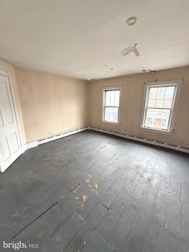 unfurnished room with a baseboard heating unit and dark wood-style floors