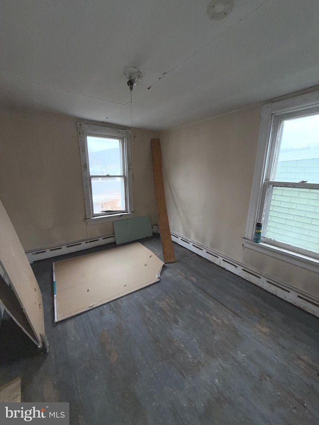 unfurnished room featuring dark wood-style floors and a baseboard radiator