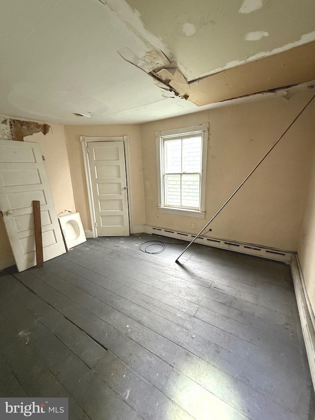 unfurnished room with a baseboard heating unit and wood-type flooring