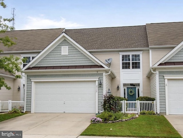 view of front of property with a standing seam roof, concrete driveway, and fence