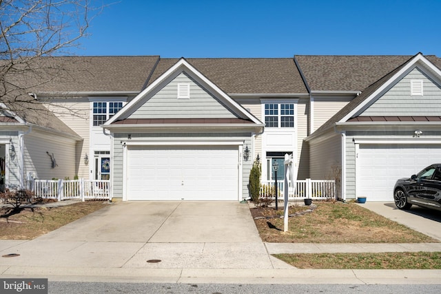 traditional-style house with a garage, roof with shingles, concrete driveway, and fence