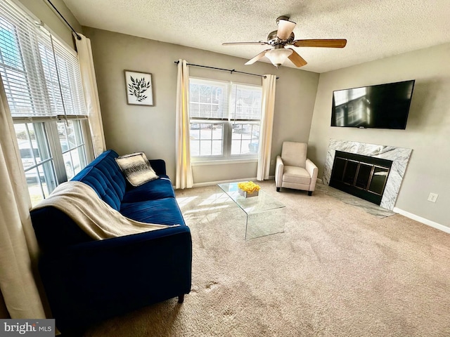 living room featuring baseboards, a premium fireplace, a ceiling fan, and carpet flooring