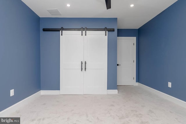 unfurnished bedroom featuring carpet floors, recessed lighting, baseboards, and a barn door