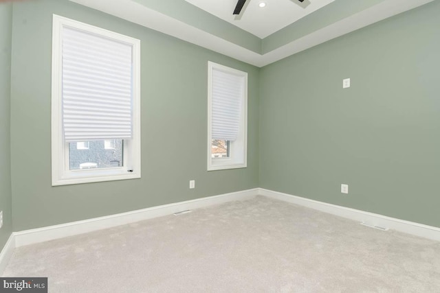 carpeted spare room featuring a ceiling fan and baseboards