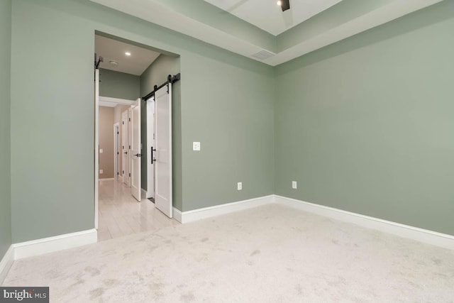 unfurnished bedroom featuring carpet flooring, baseboards, and a barn door