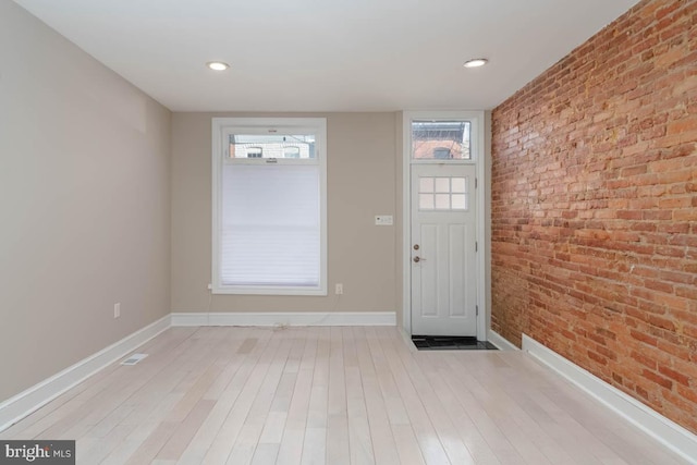 entrance foyer with light wood-style floors, brick wall, baseboards, and recessed lighting