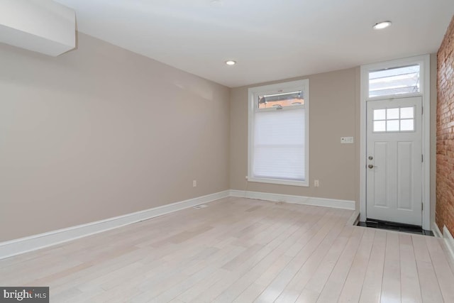 foyer with recessed lighting, brick wall, baseboards, and light wood finished floors