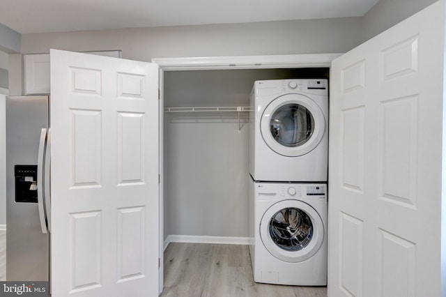 washroom with laundry area, baseboards, light wood-style floors, and stacked washer / dryer