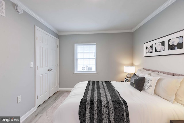 bedroom featuring light wood-style floors, visible vents, crown molding, and baseboards