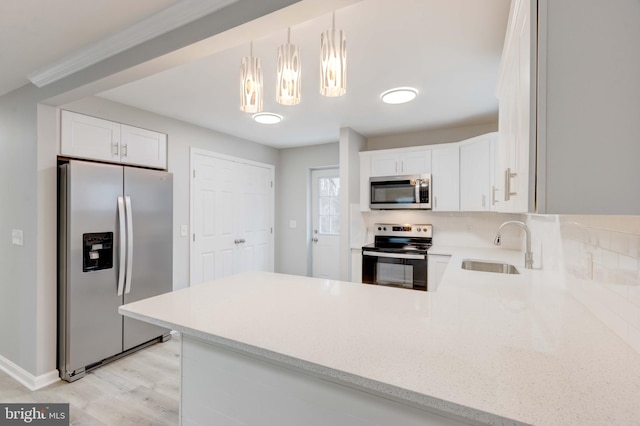 kitchen with a sink, white cabinetry, light countertops, appliances with stainless steel finishes, and decorative light fixtures