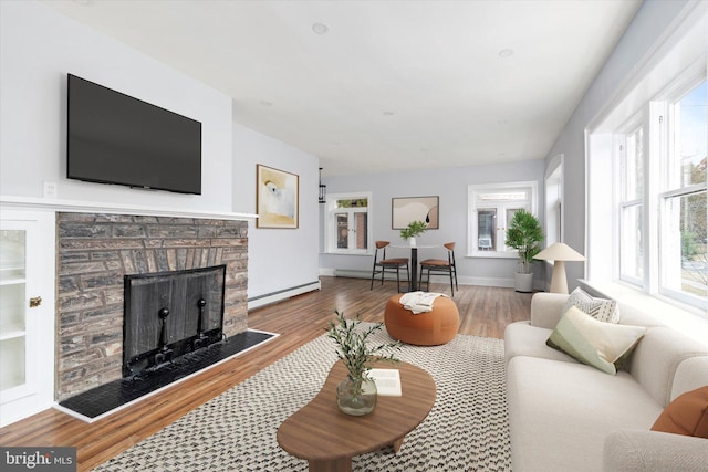 living area with baseboards, a fireplace, baseboard heating, and wood finished floors