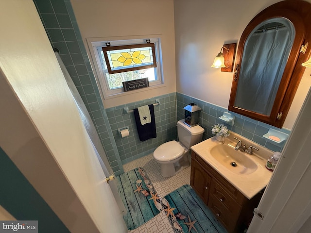 full bathroom featuring toilet, a wainscoted wall, tile patterned flooring, vanity, and tile walls