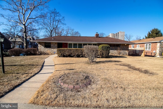 single story home featuring a front yard, stone siding, fence, and a chimney