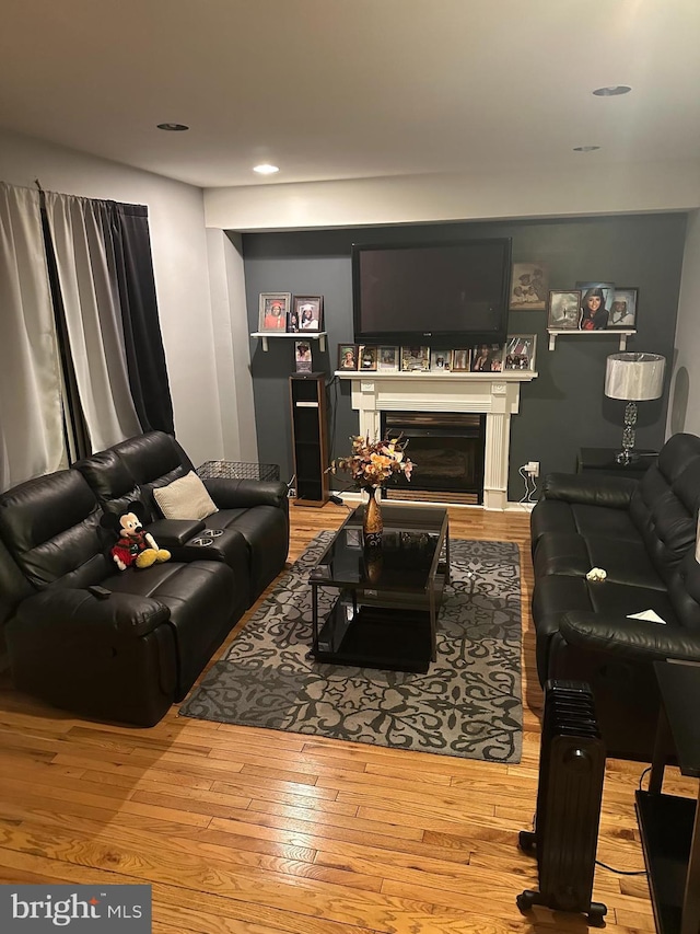 living room with recessed lighting, hardwood / wood-style floors, and a glass covered fireplace