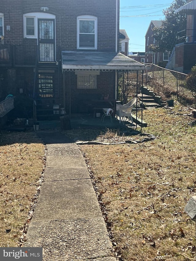 view of front of house featuring entry steps, brick siding, and fence