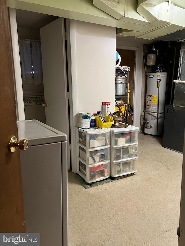 basement featuring light floors, water heater, and washer / clothes dryer