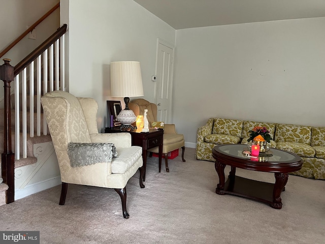 living area featuring stairs and carpet