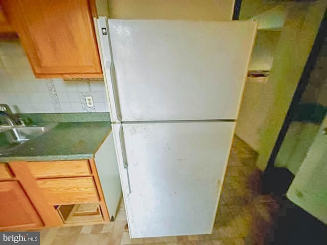 kitchen featuring tasteful backsplash, freestanding refrigerator, and a sink