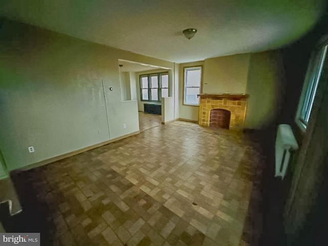 unfurnished living room featuring baseboards and a tile fireplace