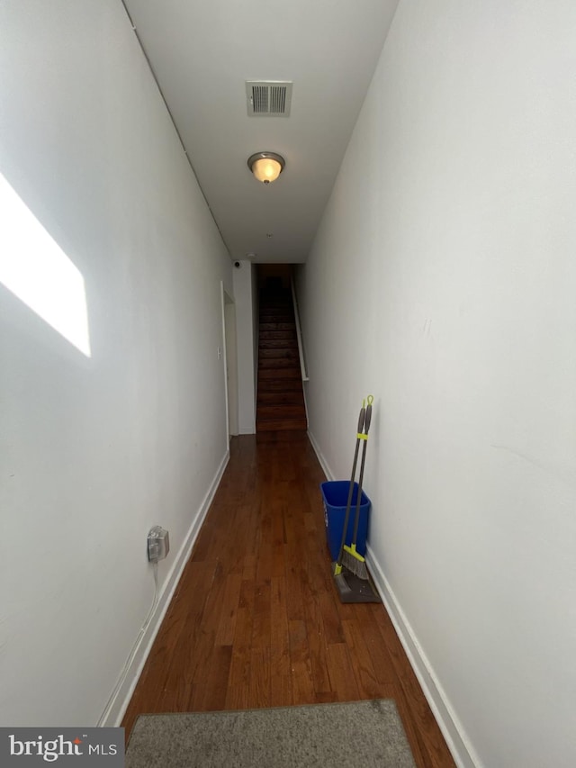 corridor with visible vents, dark wood finished floors, stairway, and baseboards