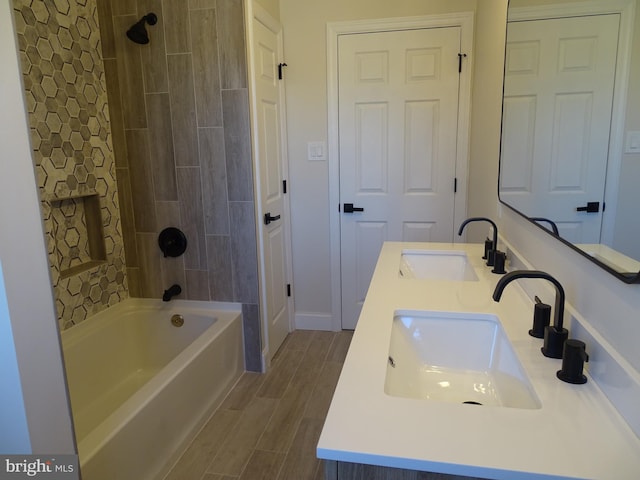 full bathroom with wood finish floors, a sink, bathing tub / shower combination, and double vanity