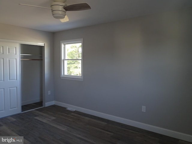 unfurnished bedroom with a ceiling fan, a closet, baseboards, and dark wood-style flooring