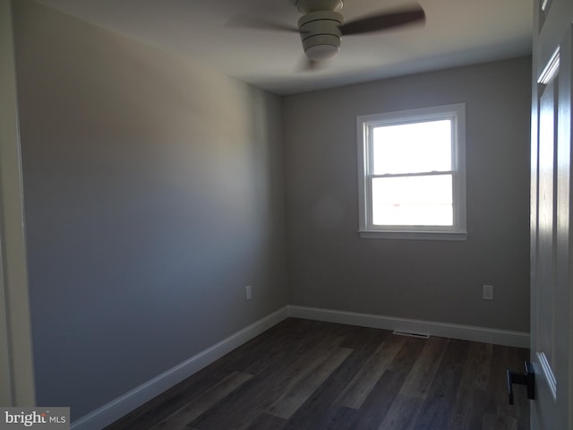 unfurnished room featuring a ceiling fan, visible vents, dark wood finished floors, and baseboards