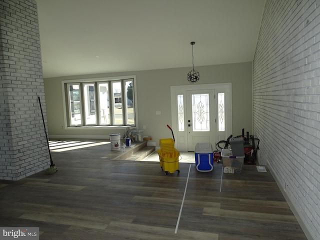 interior space with a healthy amount of sunlight, dark wood finished floors, and brick wall