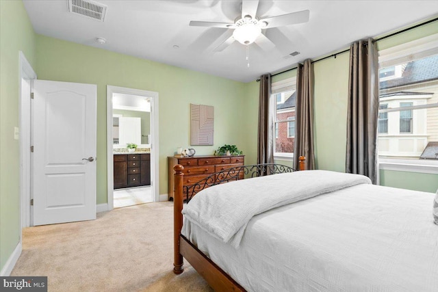 bedroom featuring light carpet, ensuite bathroom, visible vents, and baseboards