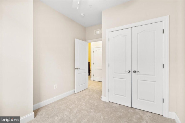 unfurnished bedroom featuring light carpet, baseboards, and a closet