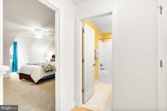 bedroom featuring light carpet, light tile patterned floors, a ceiling fan, and ensuite bathroom