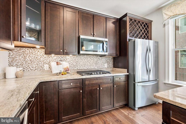 kitchen with glass insert cabinets, dark brown cabinetry, and appliances with stainless steel finishes