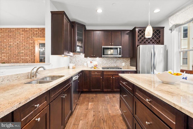 kitchen featuring a sink, dark brown cabinets, appliances with stainless steel finishes, tasteful backsplash, and pendant lighting