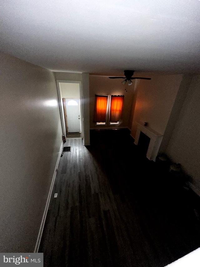 hallway featuring visible vents, baseboards, and dark wood finished floors