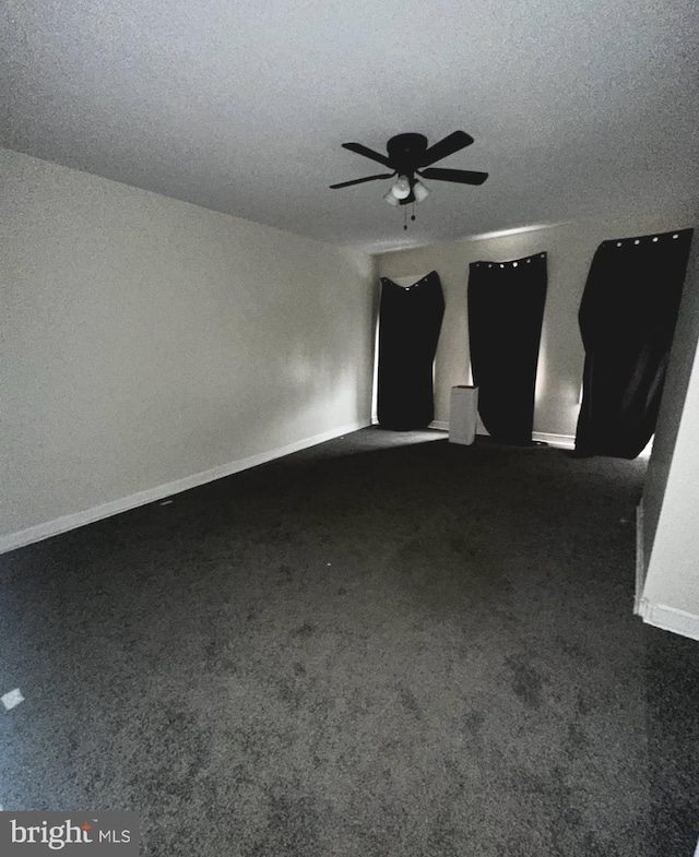 carpeted empty room with a textured ceiling, a ceiling fan, and baseboards