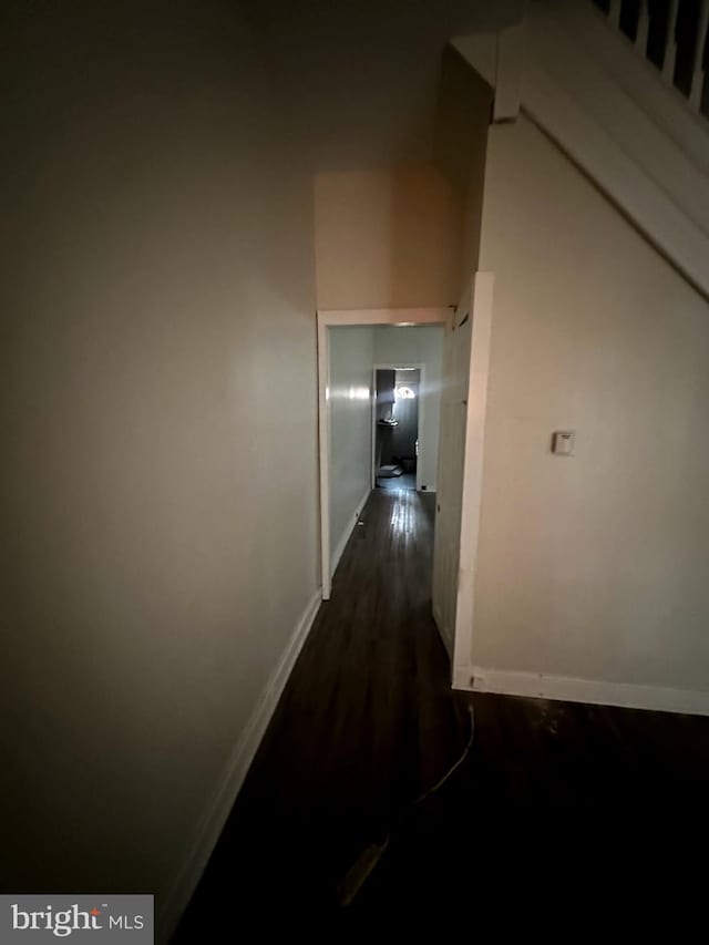 hall featuring dark wood-style flooring and baseboards