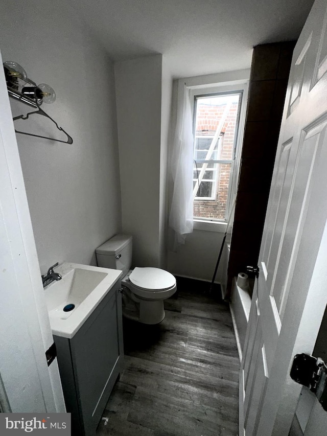 bathroom with baseboards, vanity, toilet, and wood finished floors