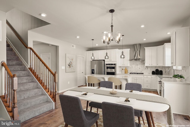 dining space with visible vents, wood finished floors, stairs, a chandelier, and recessed lighting